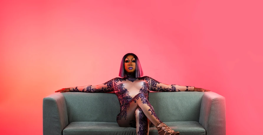 a woman sitting on a couch in an all - over bodysuit