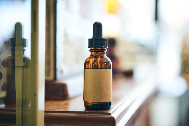 small bottle containing an e - liquid on counter in front of windows