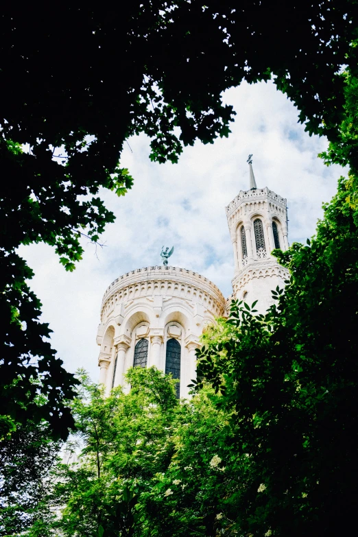 a white building is seen through the trees