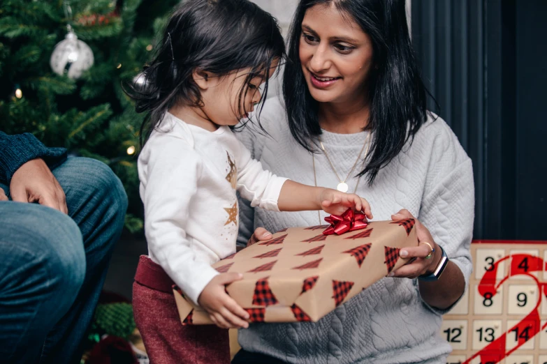 a woman in white shirt holding a little girl and gift box