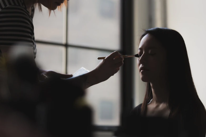 a woman is having her makeup done at a wedding