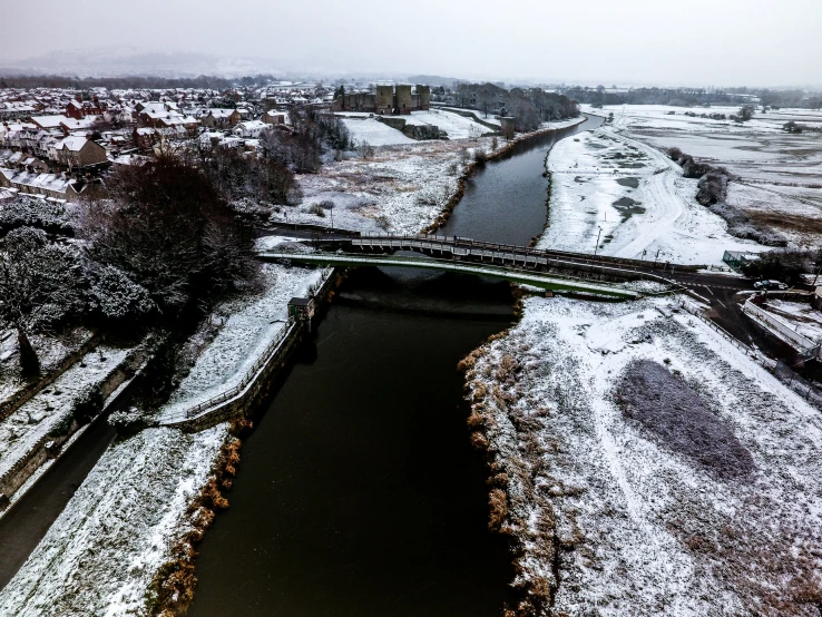 a snow covered field with a bridge and a river