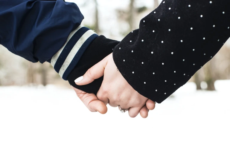 two people holding hands with snow on the ground