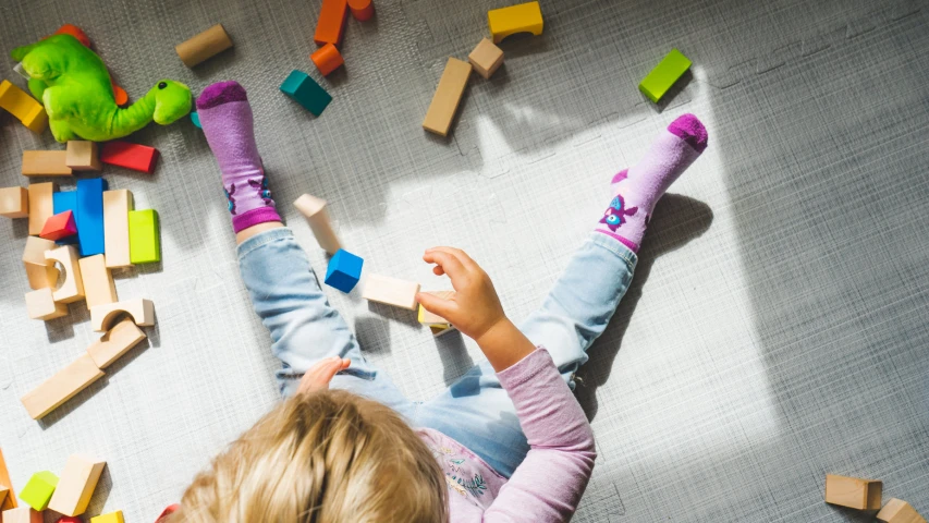 a child plays with block toys lying on the floor