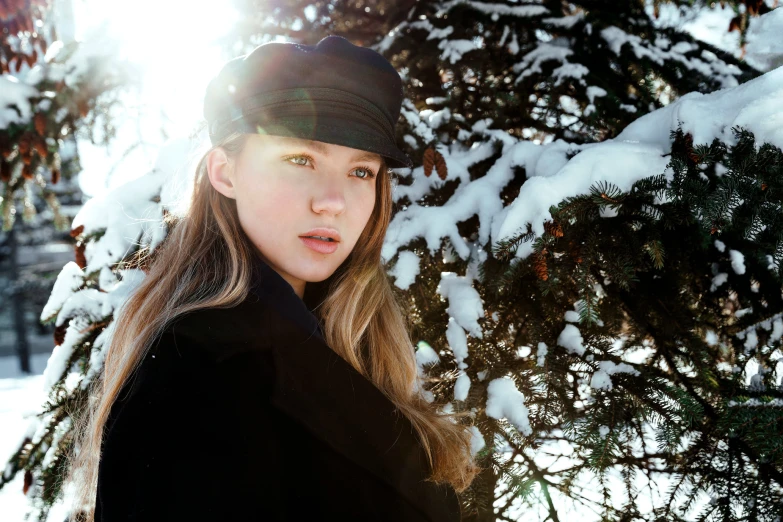 woman with ponytail standing in front of tree under snow