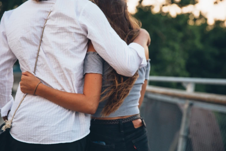 a couple standing close together hugging on the bridge