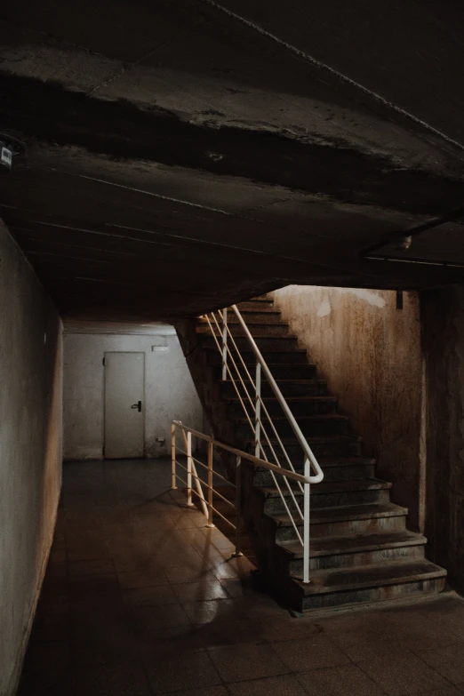 a long hallway with concrete stairs and a door leading into a dark room