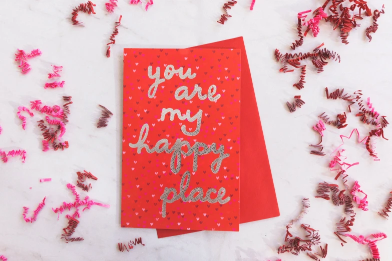 red paper streamers and pink and silver confetti scattered on white surface