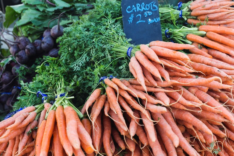 a pile of carrots for sale in a farmers market