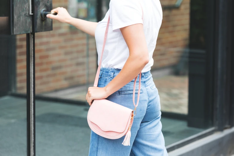 a woman holding onto a pink bag next to a building