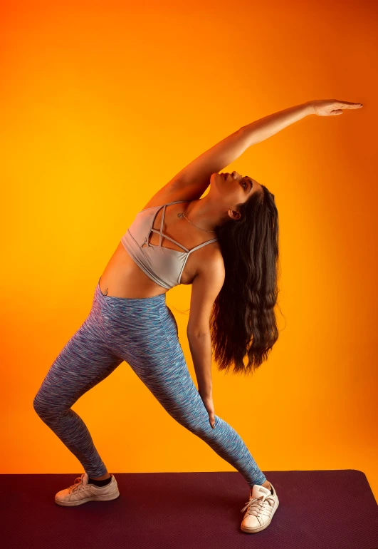 a woman in yoga clothing stretching her arm and leg on the mat