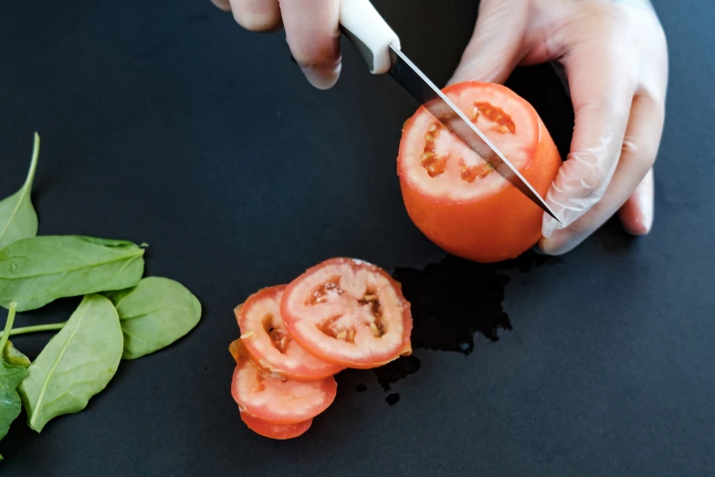 a person  up a tomato on a black surface