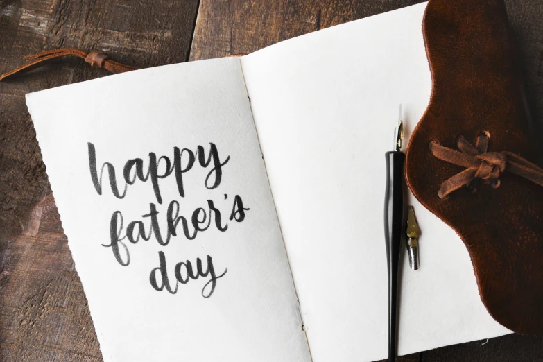 a happy father's day handwritten card and a pen