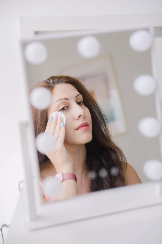 the woman is checking her make up in front of the mirror