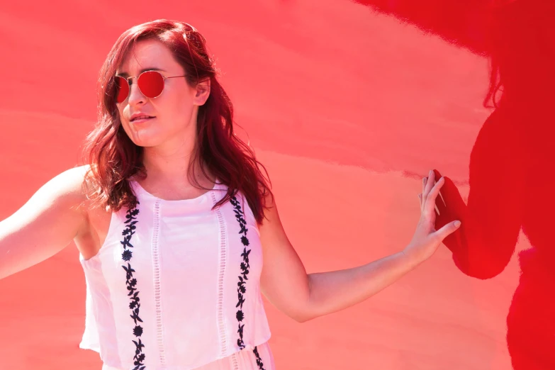 a woman posing in front of an image of a red - stained wall