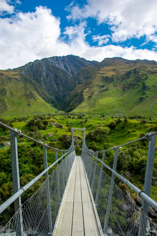 a wooden bridge that is surrounded by a green hillside