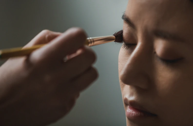 an asian woman is putting her makeup on