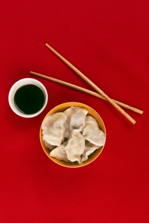 two chopsticks in a small bowl and a couple of dumplings