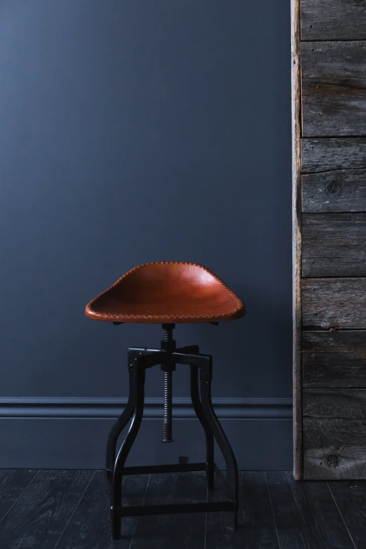 a brown chair sits against a blue wall