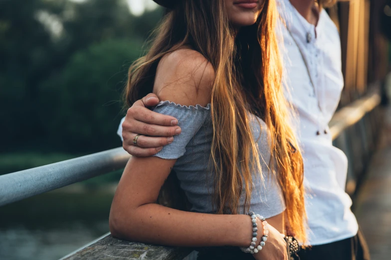 a woman holding her hair while leaning on a man