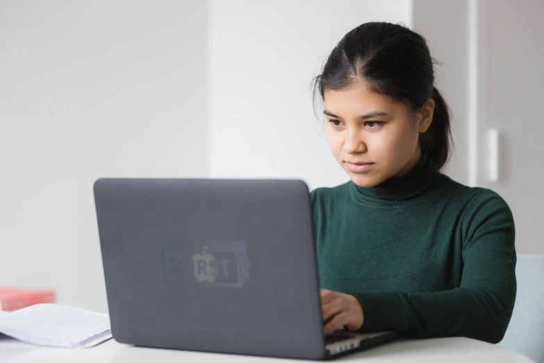 woman using laptop computer at white table in bright room