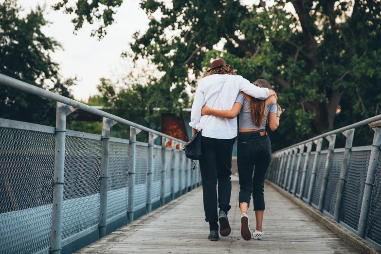 two women walk together on a bridge