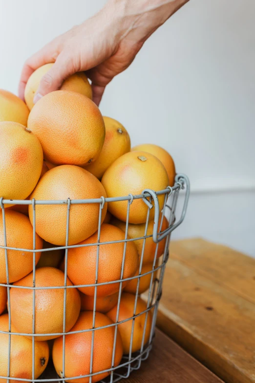 a basket full of oranges being held by a hand