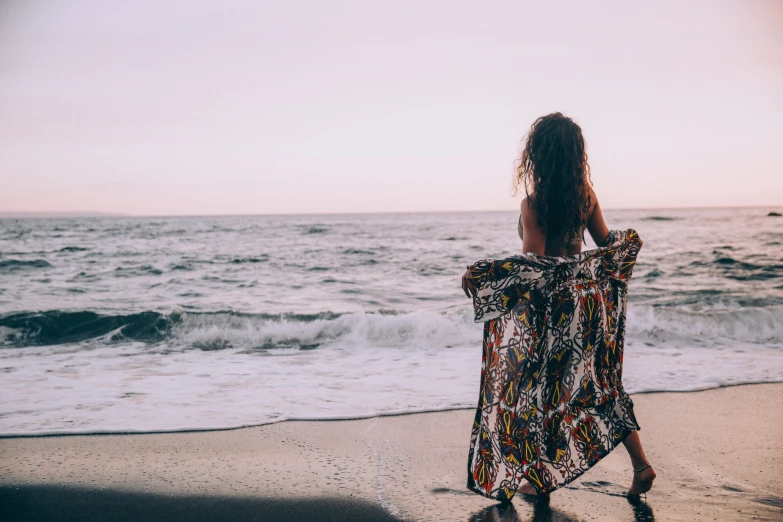 a girl is on the beach in front of the waves