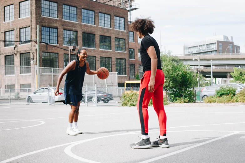 two young women are playing with a basketball outside