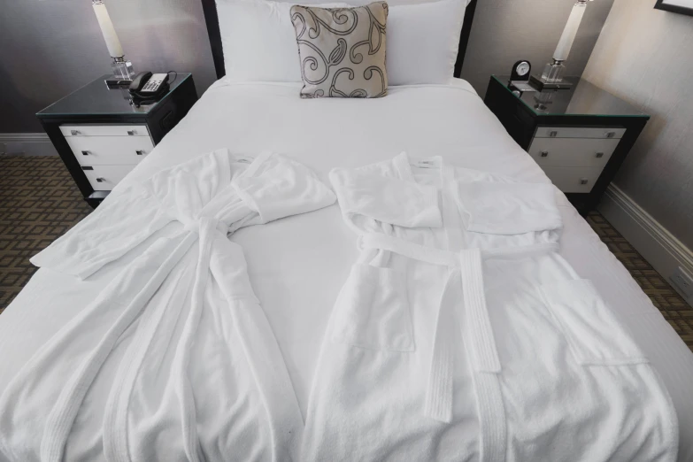 the folded robe and matching pillow cover are placed on a white bed
