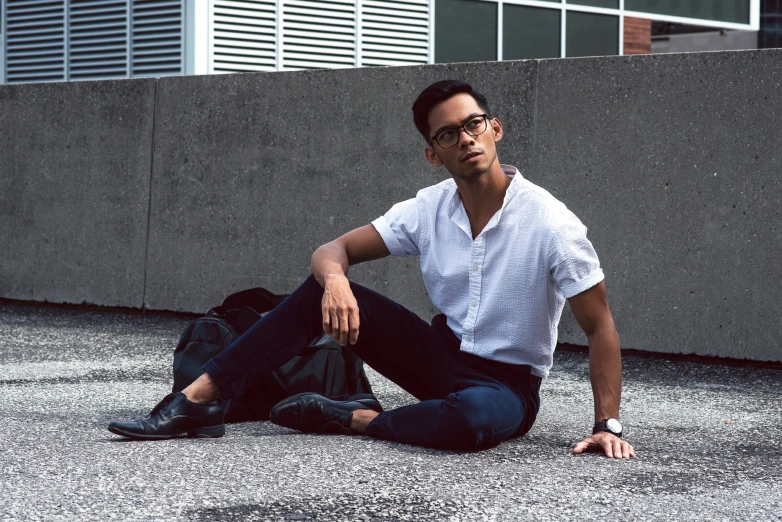 a man in glasses is sitting on the floor