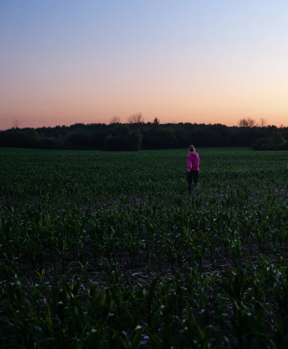 the woman is in the middle of a field in the evening