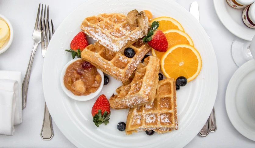 a white plate with waffles, fruit, and pancakes