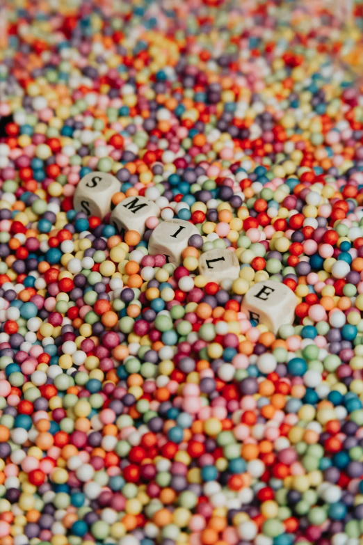 multicolored candy sprinkles spread over a letter spelling board