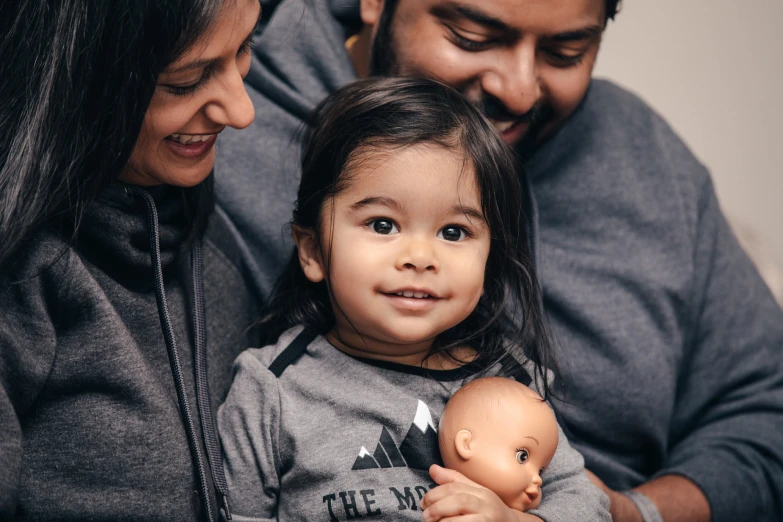 a woman, man and small girl holding a doll