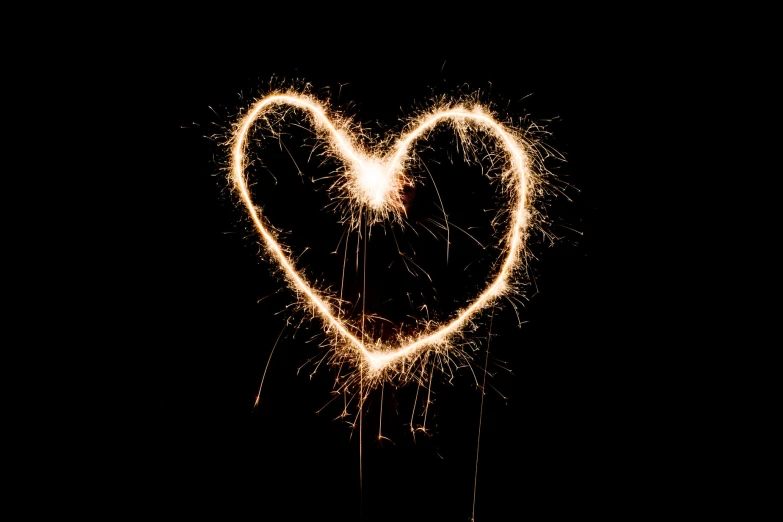 a heart - shaped object made out of sparklers on a black background