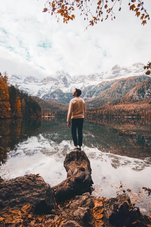 a man standing at the edge of a lake looking into the sky