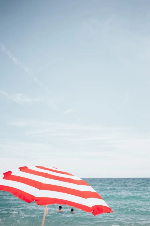 red and white striped umbrella on the beach with blue skies