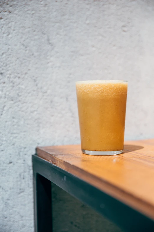 an orange drink in a glass sitting on top of a table