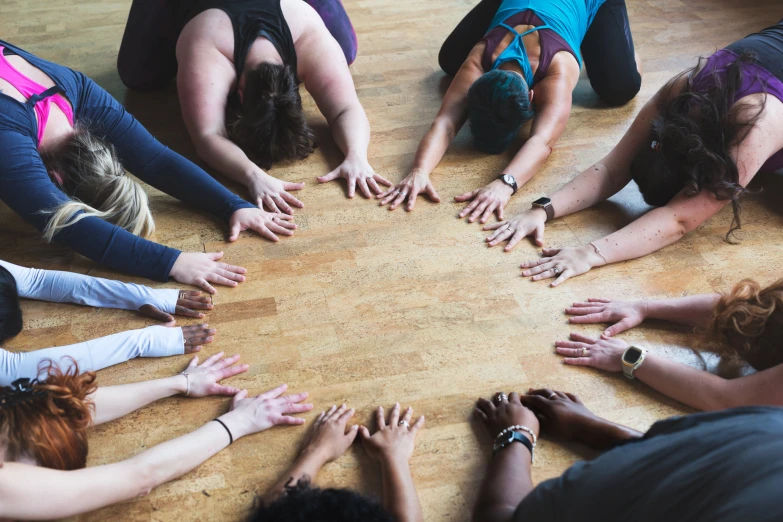 group of yoga students reaching out to surround a circle