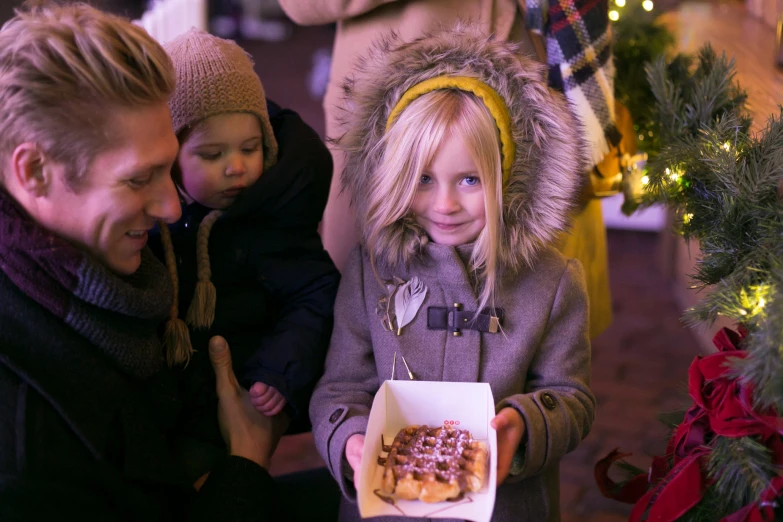 two adults and a small child eating a pastry