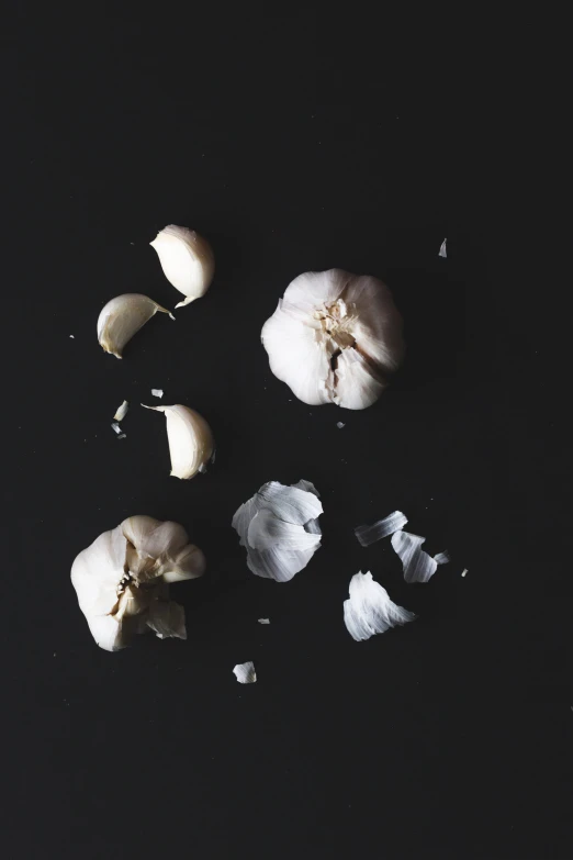 a whole garlic and slices of it on a black surface