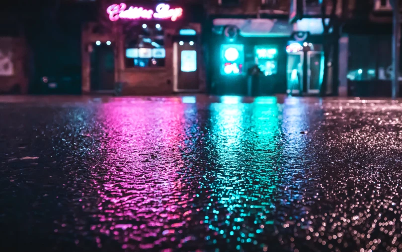 colorful lights shine brightly over wet pavement in the dark