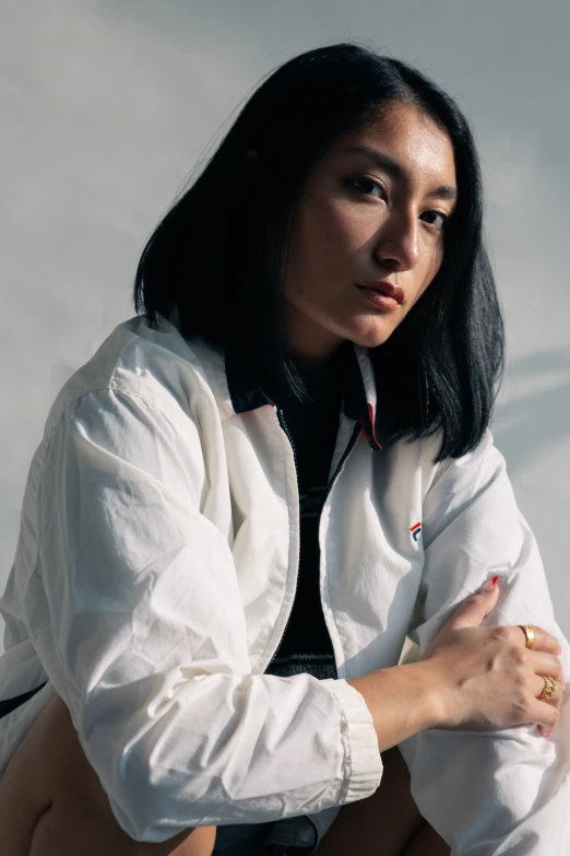 an asian woman wearing a white jacket, black shirt and tie