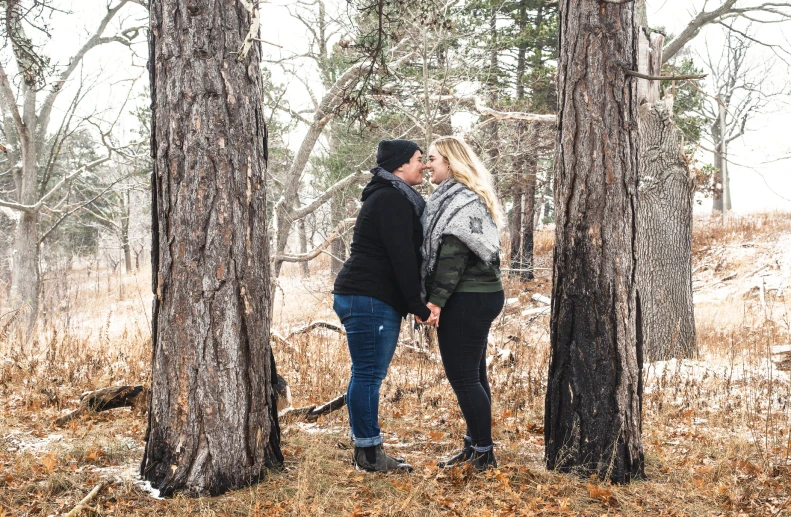 a man kissing a woman standing among the trees