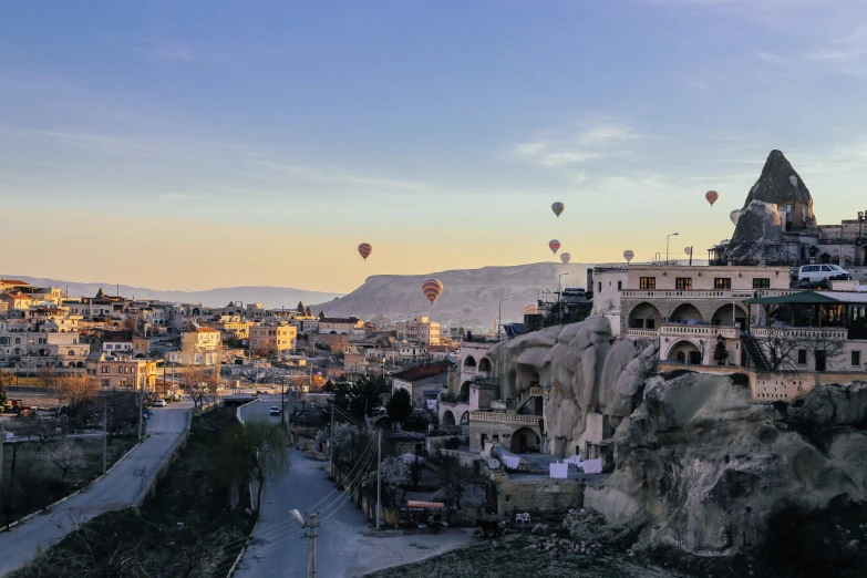 many balloons flying in the air over houses and buildings