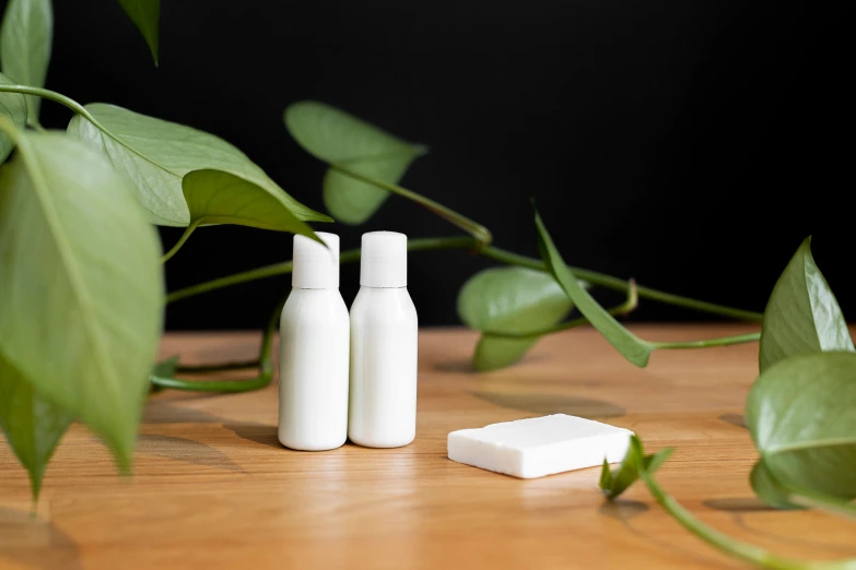 the three bottles and one container are sitting on a table