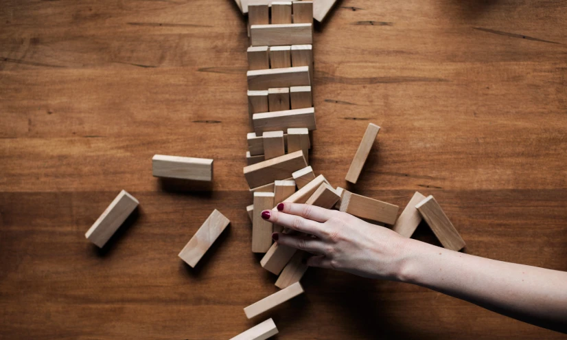 a person grabbing onto some wood pieces with a knife