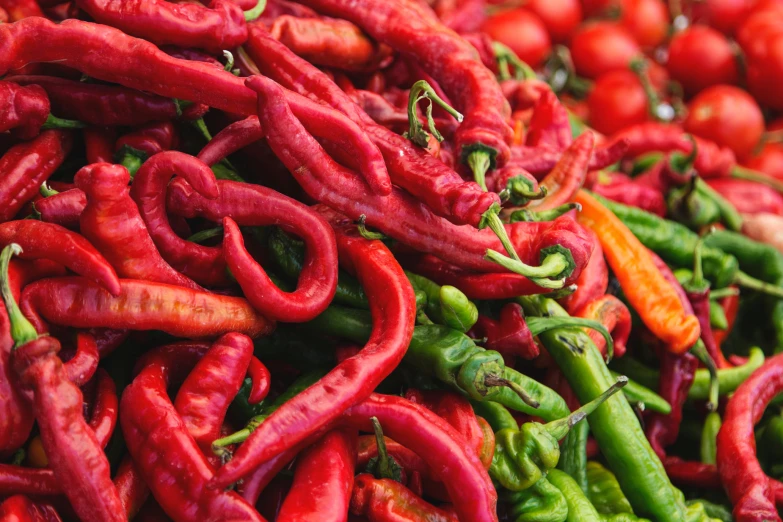 several piles of different colored peppers in various stages of ripeness