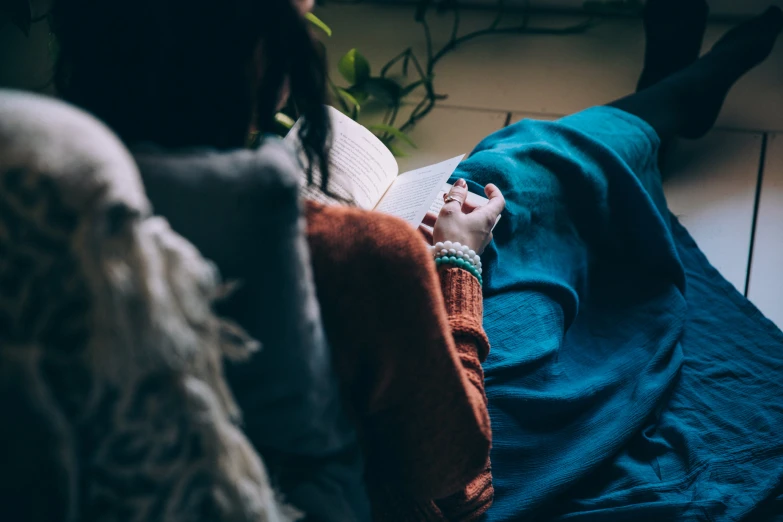 a person that is reading a book sitting on the ground